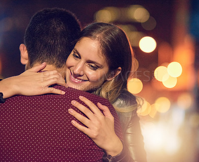 Buy stock photo Shot of a happy young couple in a warm embrace outside at night