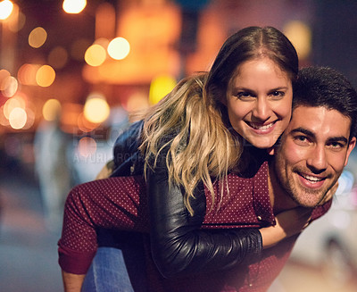 Buy stock photo Portrait of a happy young couple enjoying a piggyback ride outside at night