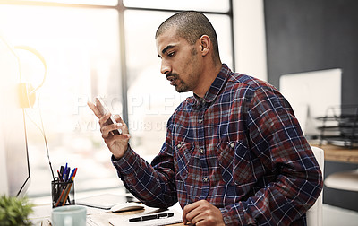 Buy stock photo Shot of a young entrepreneur texting on a cellphone in an office