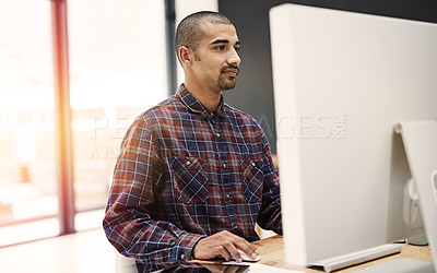 Buy stock photo Shot of a young entrepreneur working on a computer in an office