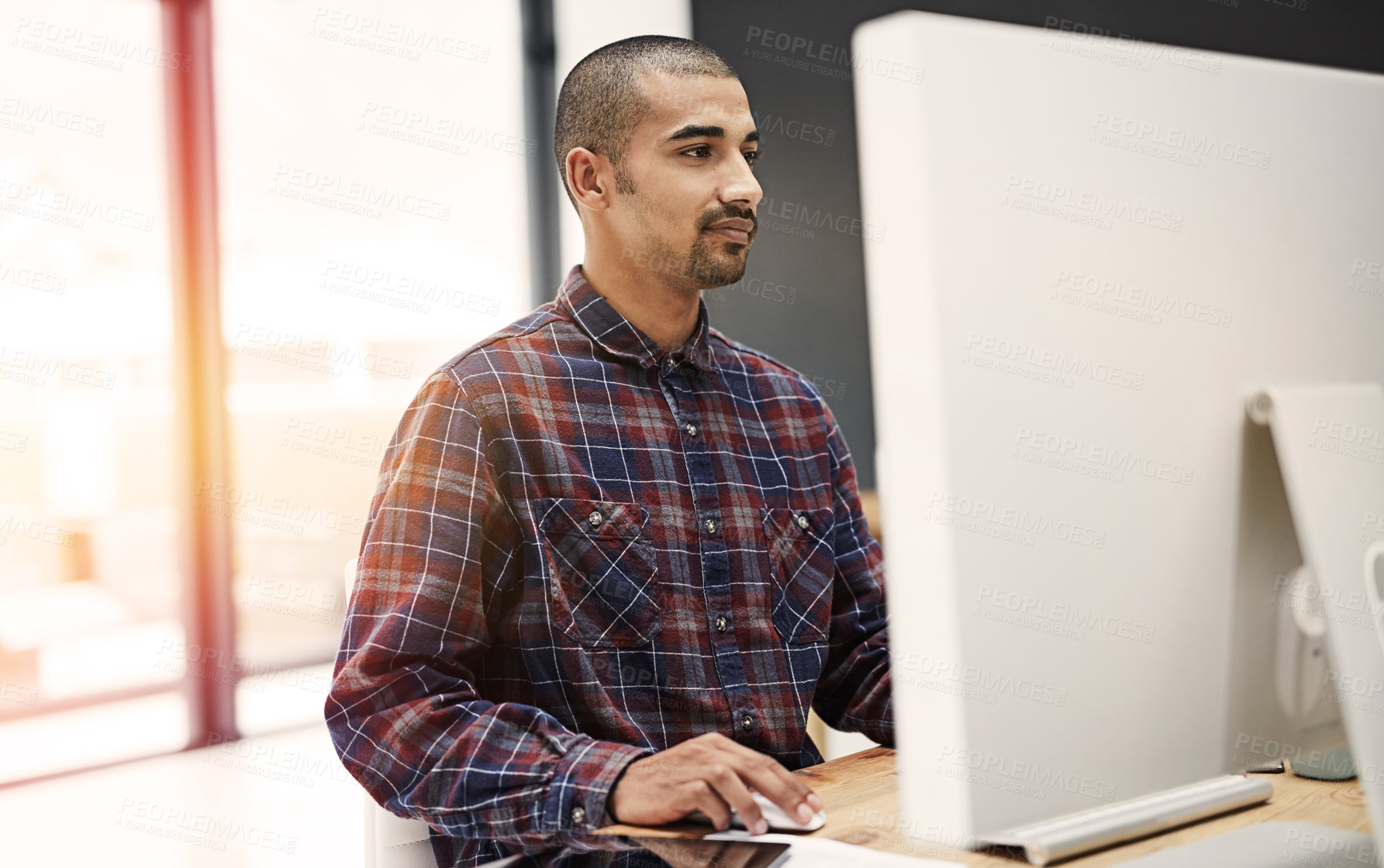 Buy stock photo Shot of a young entrepreneur working on a computer in an office