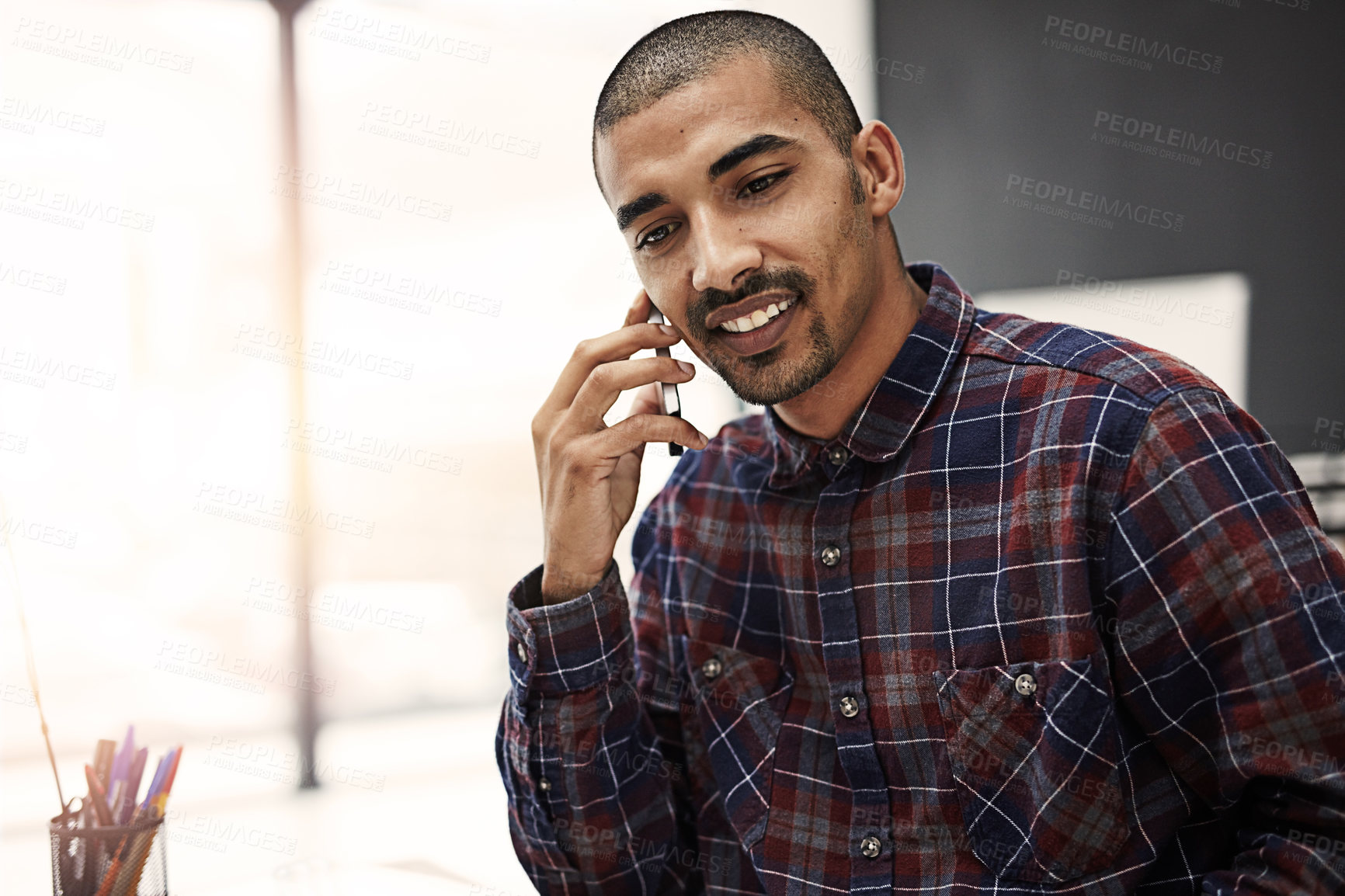 Buy stock photo Shot of a young entrepreneur talking on a cellphone in an office