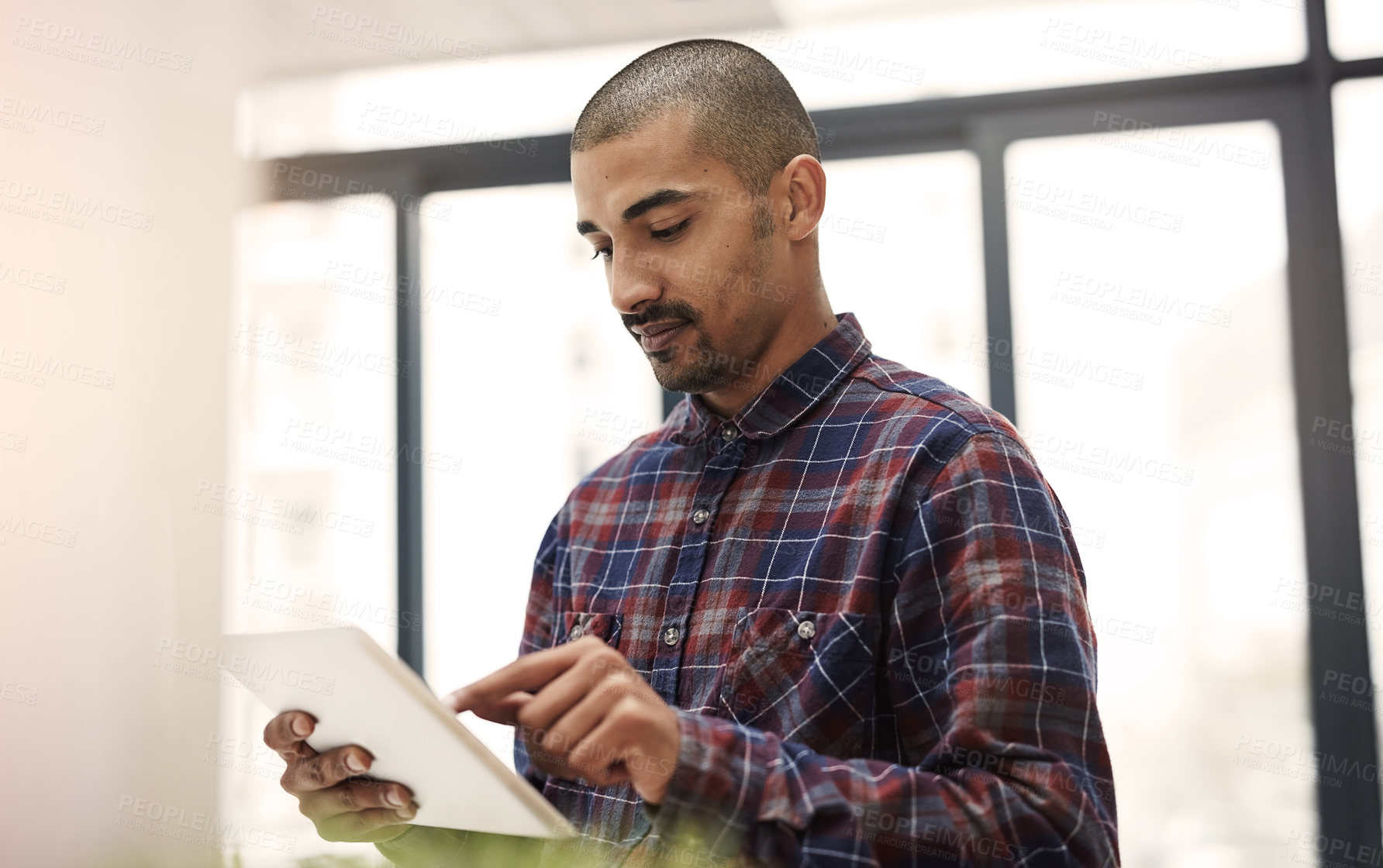 Buy stock photo Shot of a young entrepreneur working on a digital tablet in an office