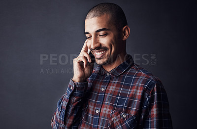 Buy stock photo Studio shot of a young man talking on a cellphone against a dark background