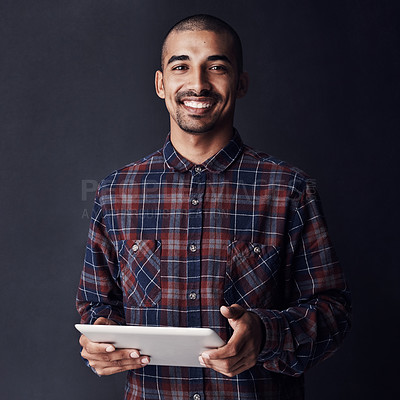 Buy stock photo Studio portrait of a young man using a digital tablet against a dark background