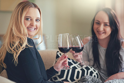 Buy stock photo Portrait of two young friends enjoying a glass of wine together at home