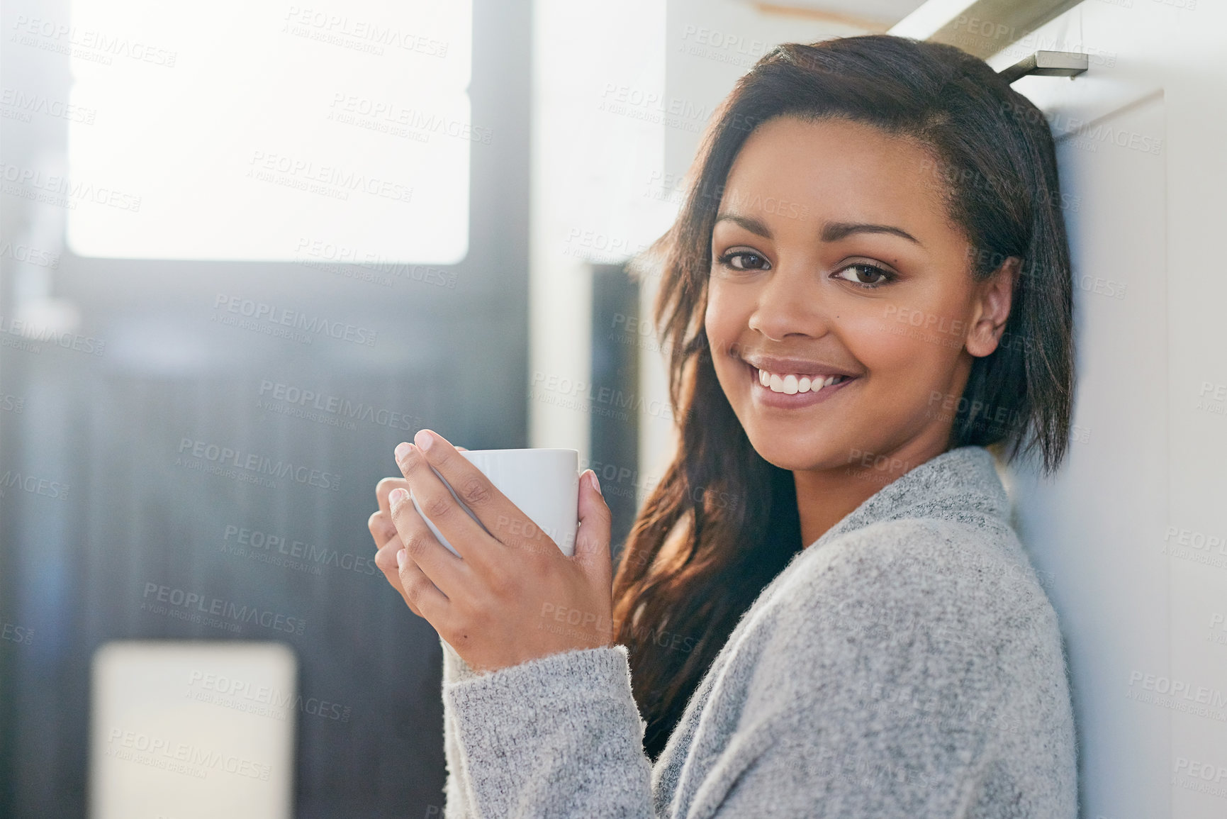 Buy stock photo Portrait of a pretty young woman enjoying a cup of coffee in her kitchen in the morning