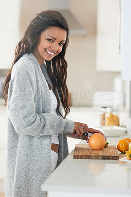 Buy stock photo Portrait of a happy young woman preparing a breakfast of fruit in her kitchen at home