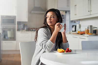 Buy stock photo Shot of young woman daydreaming while enjoying breakfast in her kitchen at home
