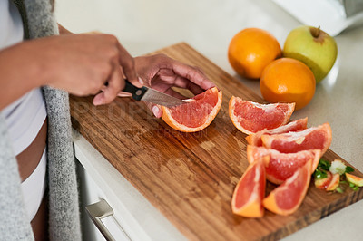 Buy stock photo Shot of an unidentifiable woman cutting fruit for breakfast in her kitchen at home