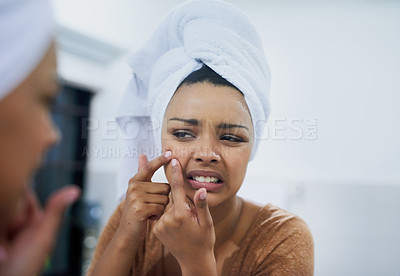 Buy stock photo Shot of a young woman frowning while examining an imperfection on her skin in the mirror