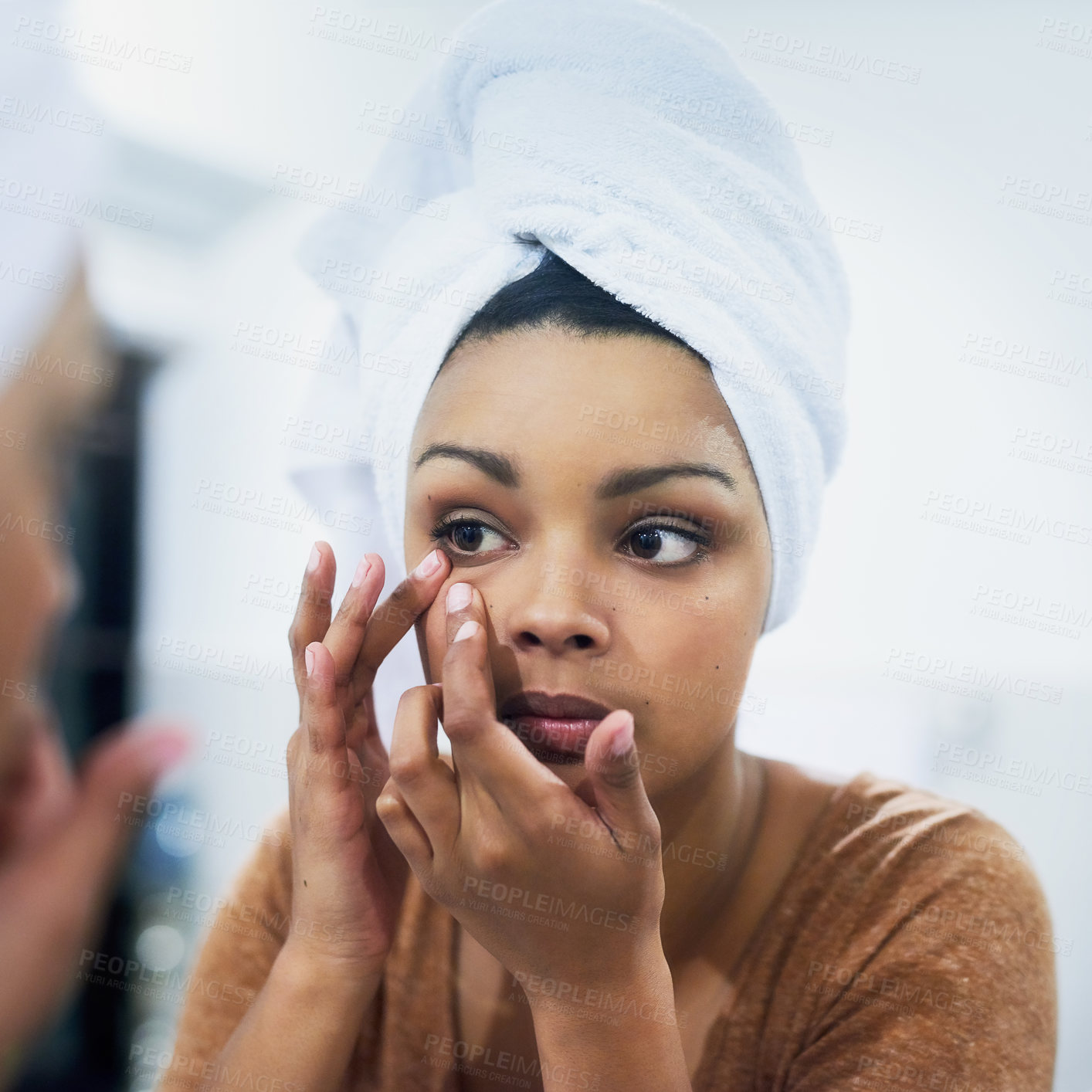 Buy stock photo Shot of a young woman adjusting her makeup in the bathroom mirror