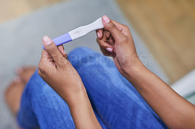 Buy stock photo Shot of an unidentifiable woman holding a pregnancy test while sitting in her bathroom