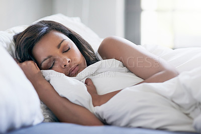 Buy stock photo Shot of a relaxed young woman sleeping in her bed at home