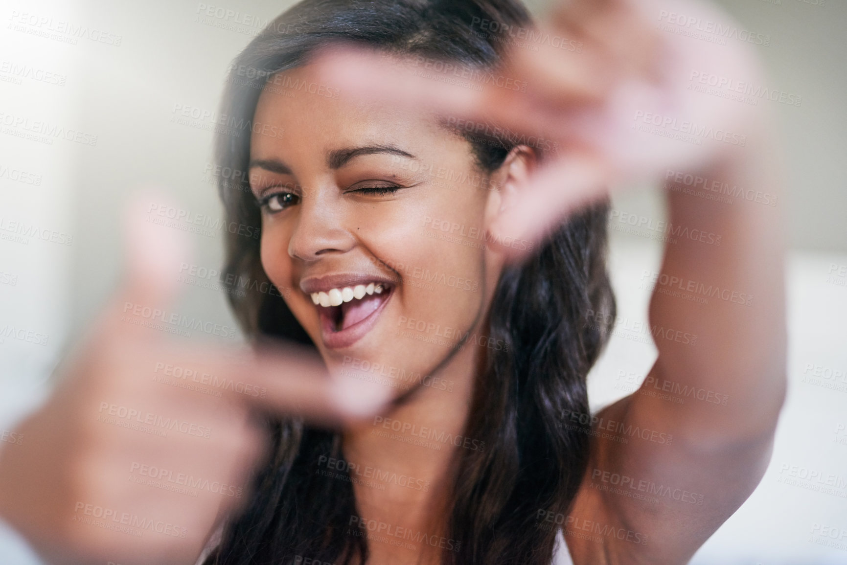 Buy stock photo Girl, finger frame and wink in home with portrait for photography symbol in morning sunshine. Woman, person and hands for shape, sign or emoji with smile for perspective with confidence in apartment