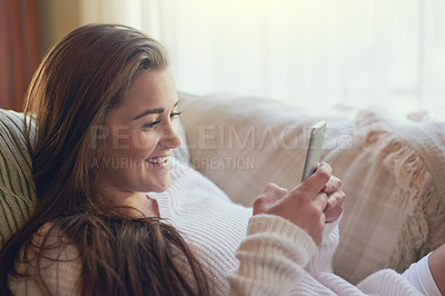 Buy stock photo Shot of a beautiful young woman texting on her cellphone at home