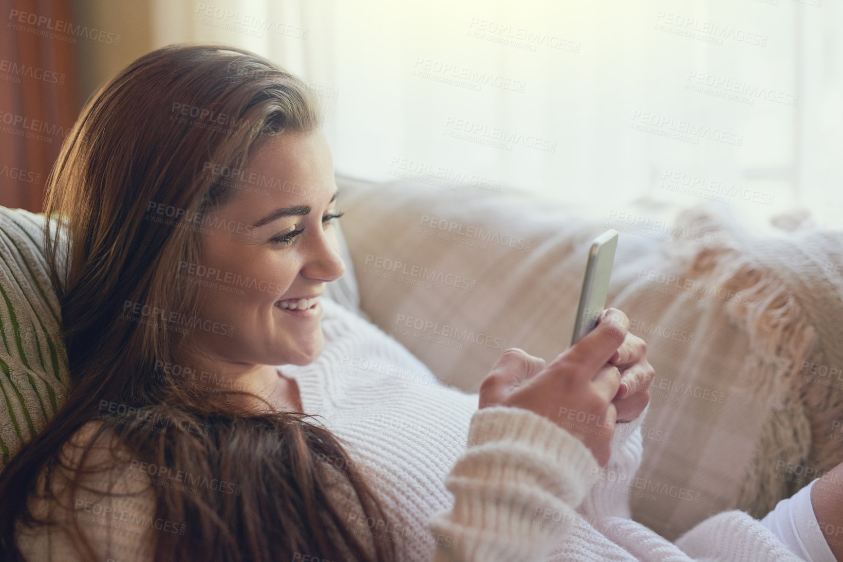 Buy stock photo Shot of a beautiful young woman texting on her cellphone at home