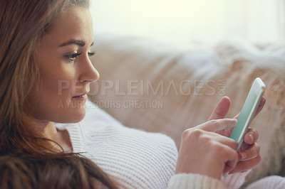 Buy stock photo Closeup shot of a beautiful young woman texting on her cellphone at home