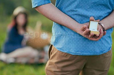 Buy stock photo Rear view shot of a man about to propose to his girlfriend with an engagement ring in a box