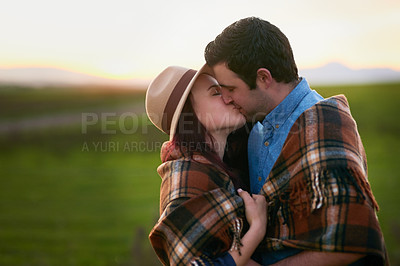 Buy stock photo Shot of an affectionate young couple sharing a kiss