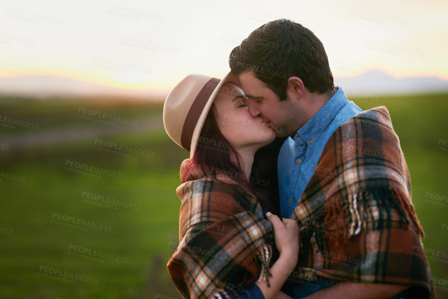 Buy stock photo Shot of an affectionate young couple sharing a kiss