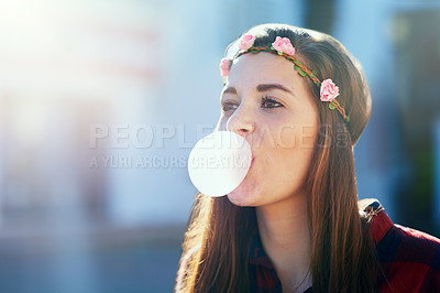 Buy stock photo Shot of an attractive young woman blowing chewing gum outside