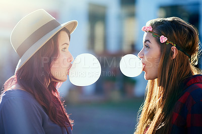 Buy stock photo Shot of two young friends blowing chewing gum while facing each other