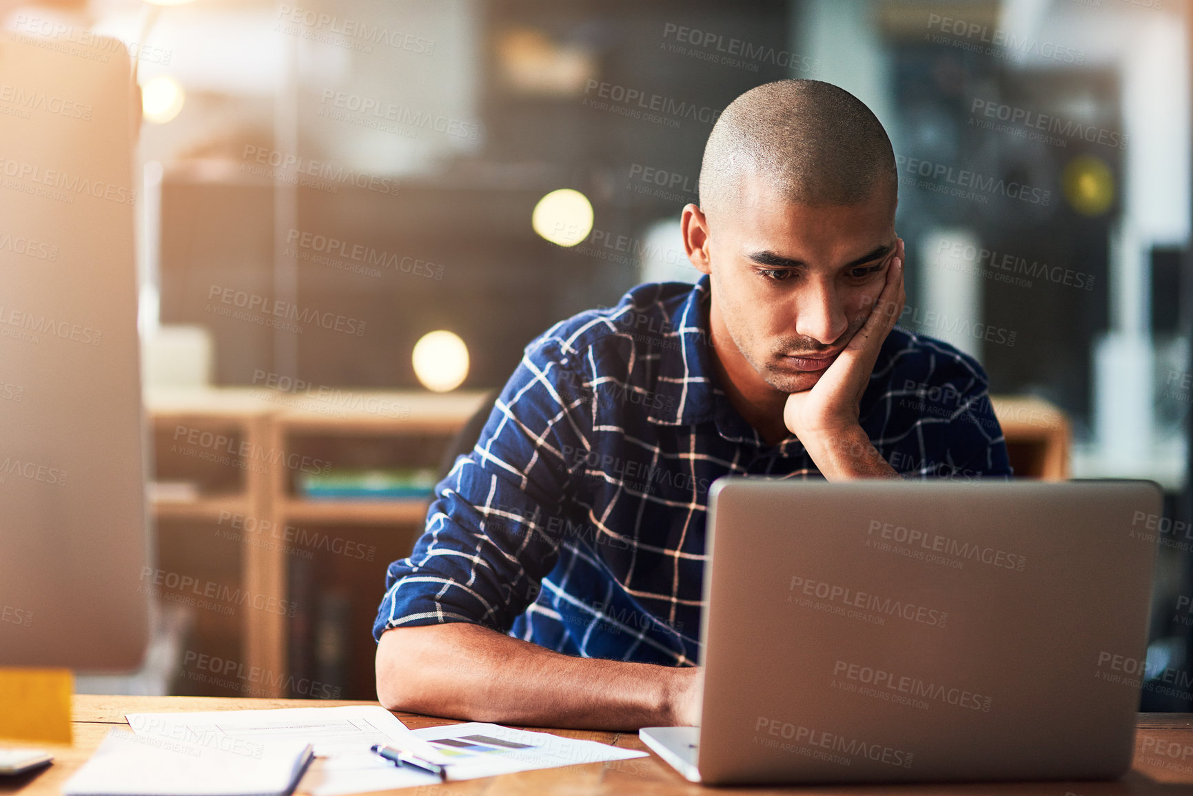 Buy stock photo Cropped shot of a young designer looking bored while working at his office desk