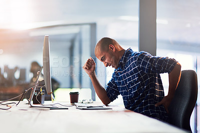 Buy stock photo Cropped shot of a young designer experiencing back pain while working at his desk