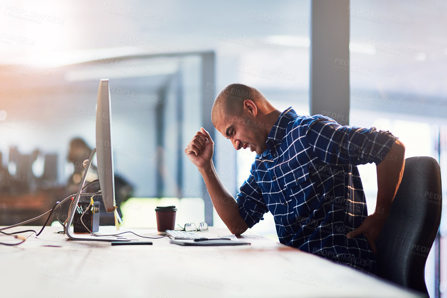 Buy stock photo Cropped shot of a young designer experiencing back pain while working at his desk