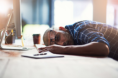 Buy stock photo Portrait of a young designer looking exhausted with his head down on his office desk