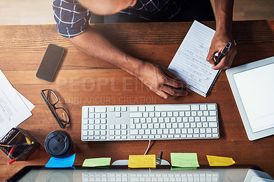 Buy stock photo High angle shot of an unidentifiable man working at his office desk