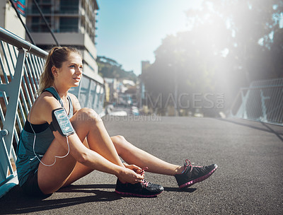 Buy stock photo Shot of a sporty young woman tying her laces before a run