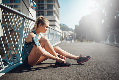 Buy stock photo Shot of a sporty young woman tying her laces before a run