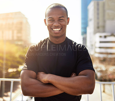 Buy stock photo Portrait of a sporty young man standing with his arms folded outdoors