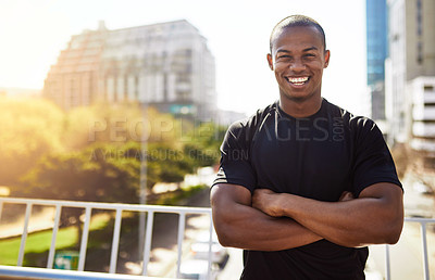 Buy stock photo Portrait of a sporty young man standing with his arms folded outdoors