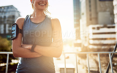 Buy stock photo Earphones, woman and runner in city with arms crossed for morning jog, exercise and outdoor workout. Athlete, training and girl with smile on bridge for running challenge, fitness or music playlist