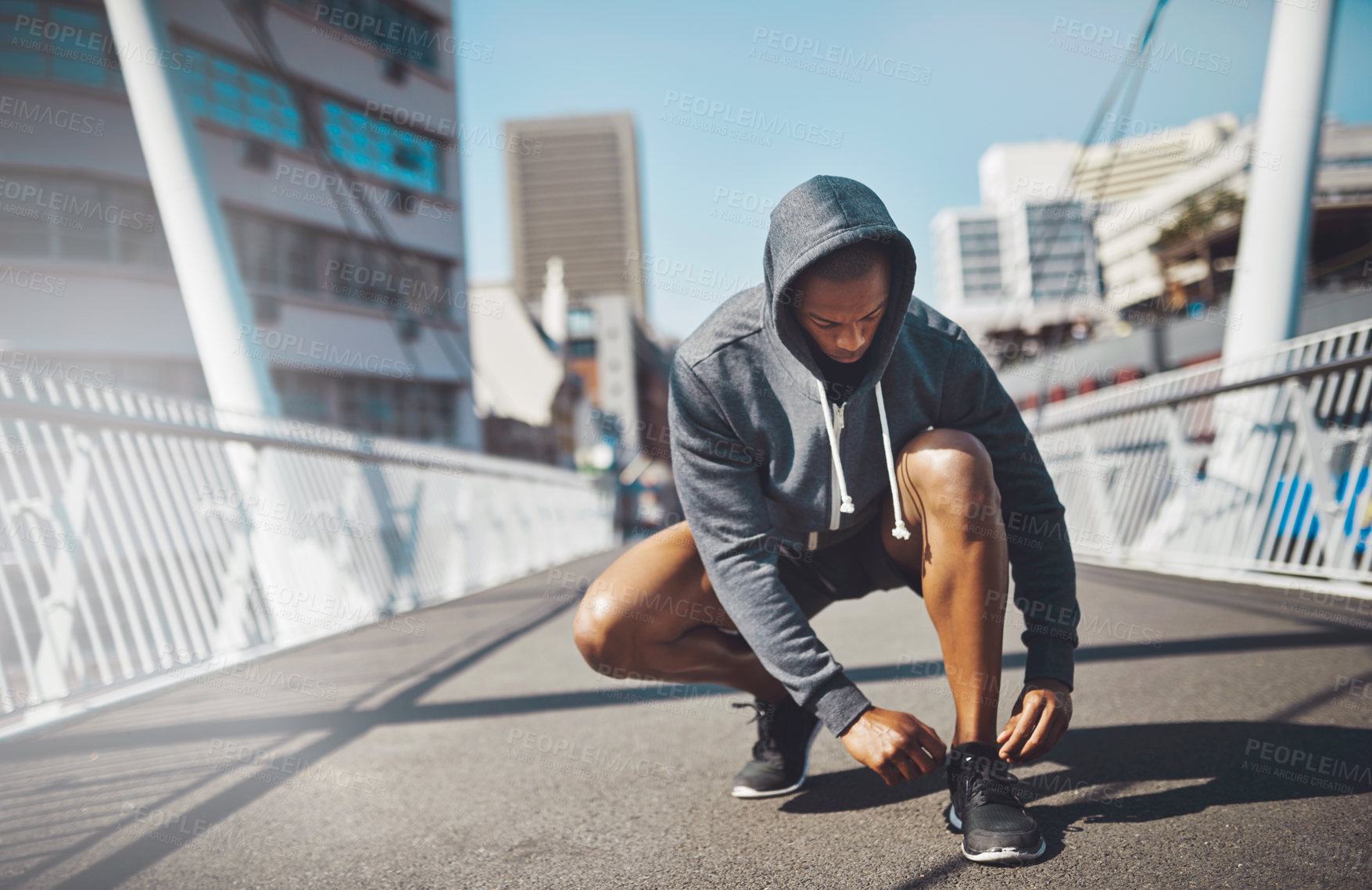 Buy stock photo Shot of a sporty young man tying his laces before a run