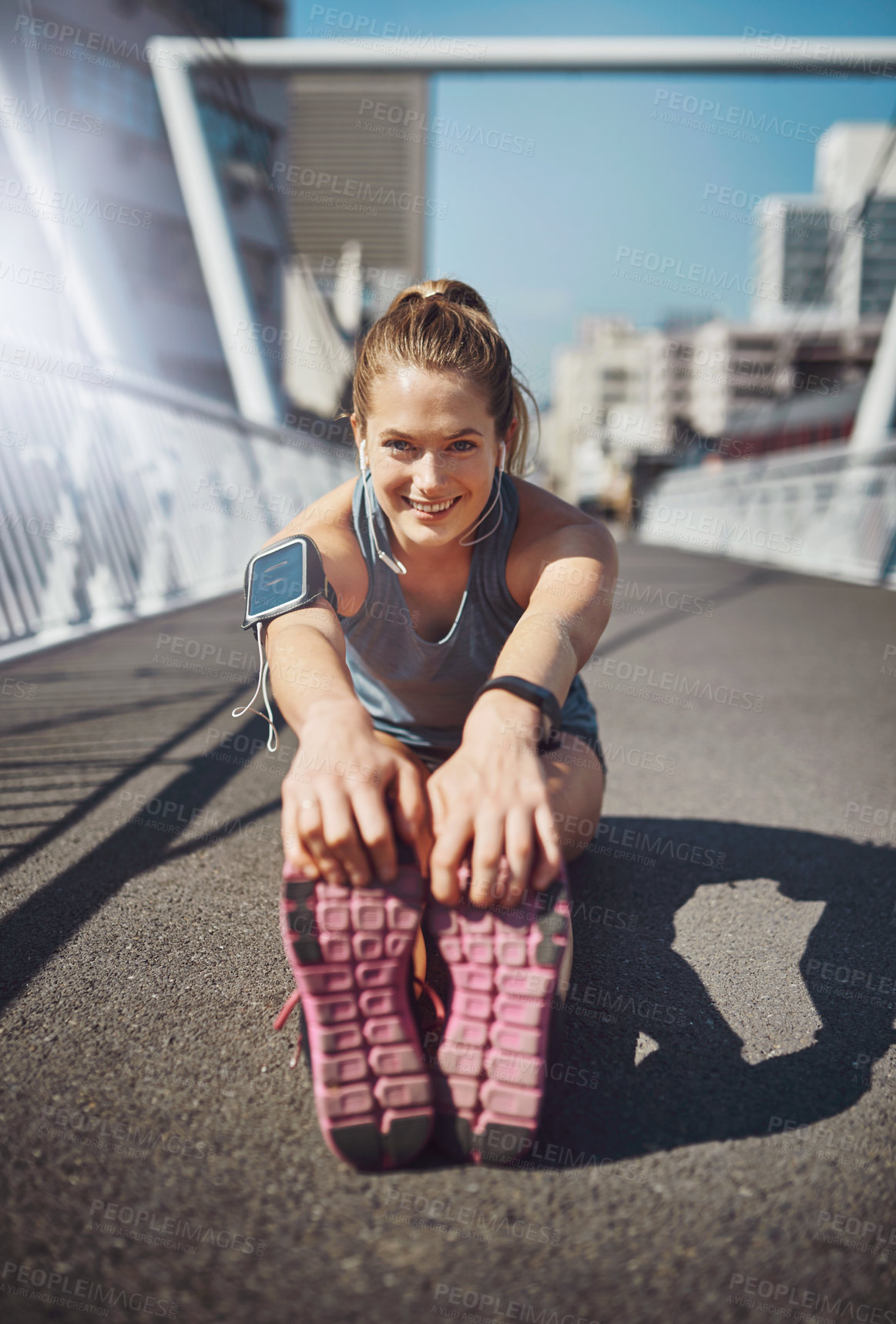 Buy stock photo Happy woman, portrait and stretching with earphones in city for fitness, exercise or workout preparation on bridge. Young, female person or runner with smile for leg or foot warm up in an urban town