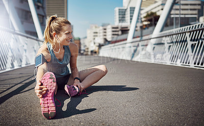 Buy stock photo Happy woman, fitness and stretching with earphones in city for exercise or workout preparation on bridge. Young, female person or runner with smile for body, leg or foot warm up in an urban town