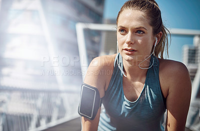 Buy stock photo Shot of a sporty young woman looking tired during a run