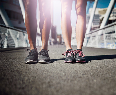 Buy stock photo Legs-only shot of two sporty people standing on a bridge