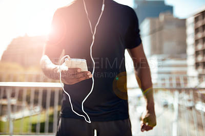 Buy stock photo Shot of a sporty young man getting his playlist ready for a run