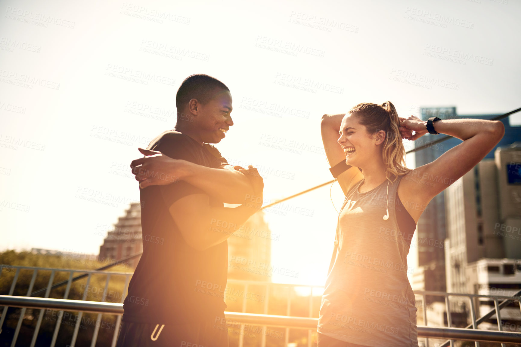 Buy stock photo Runner, man and woman with warm up on bridge with exercise, laugh and funny joke at sunrise in city. People, couple and stretching arms in street with lens flare, fitness and workout in morning