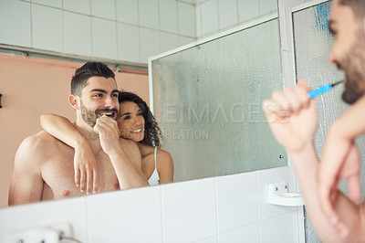 Buy stock photo Shot of a young woman hanging on her boyfriend's shoulder while he brushes his teeth