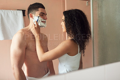 Buy stock photo Shot of a young woman shaving her boyfriend's face in the bathroom