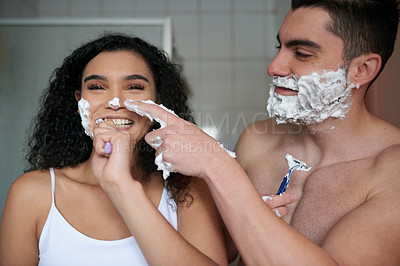 Buy stock photo Portrait of an attractive young woman brushing her teeth while her boyfriend shaves in the bathroom
