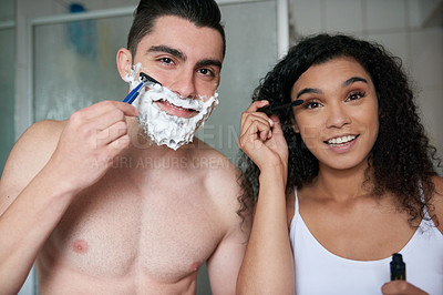 Buy stock photo Portrait of an attractive young woman applying mascara while her boyfriend shaves in the bathroom