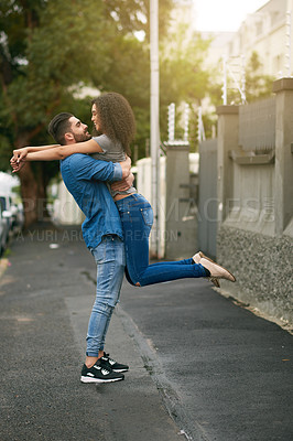 Buy stock photo Shot of a young man lifting his girlfriend while standing outside