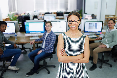 Buy stock photo Portrait of a smiling young designer standing in an office with colleagues working in the background